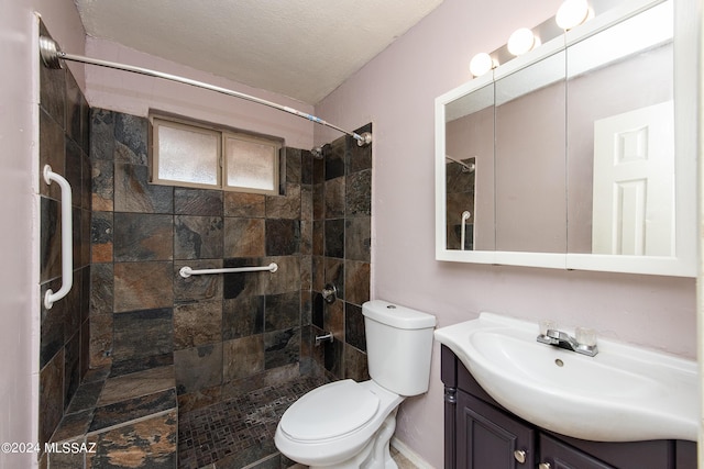 bathroom featuring a textured ceiling, vanity, a tile shower, and toilet