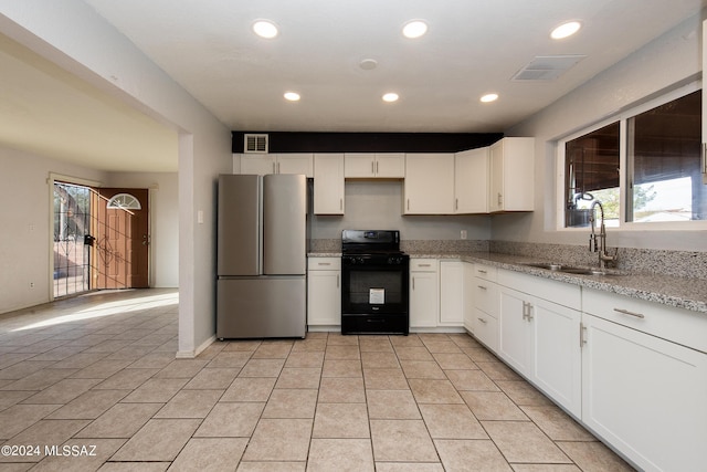 kitchen with sink, stainless steel fridge, light stone countertops, white cabinetry, and black range with gas cooktop