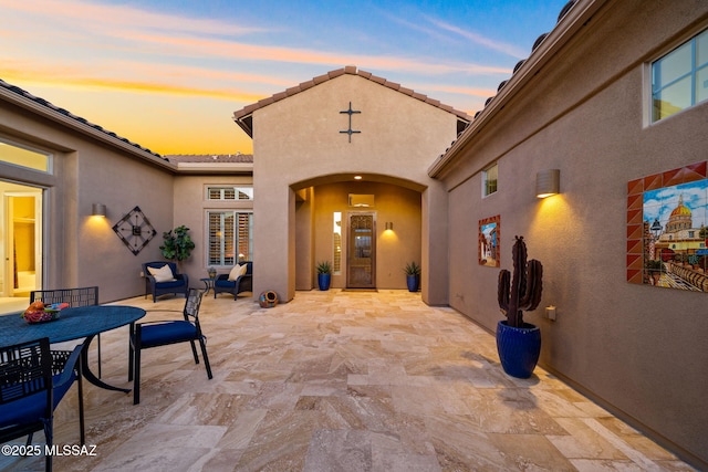 exterior entry at dusk featuring a patio