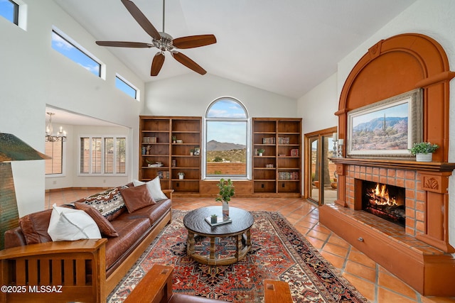 living room featuring a tiled fireplace, light tile patterned floors, ceiling fan with notable chandelier, and high vaulted ceiling