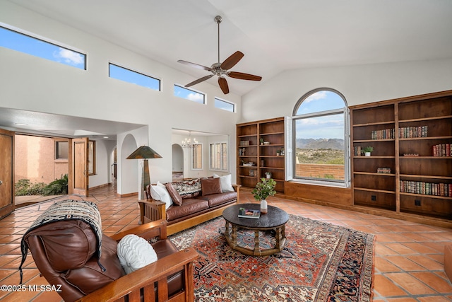 living room featuring light tile patterned floors, ceiling fan with notable chandelier, and high vaulted ceiling