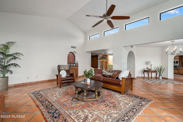 living room featuring a towering ceiling, ceiling fan with notable chandelier, and tile patterned floors