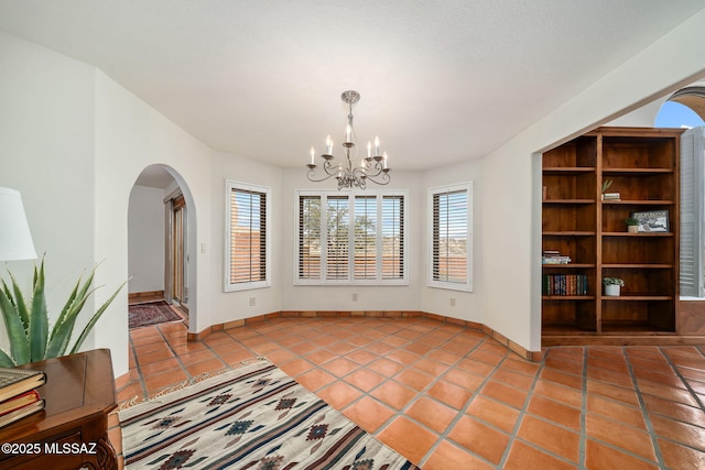 unfurnished dining area with light tile patterned floors and an inviting chandelier