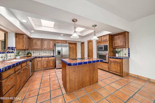 kitchen with tasteful backsplash, stainless steel appliances, sink, tile countertops, and a kitchen island