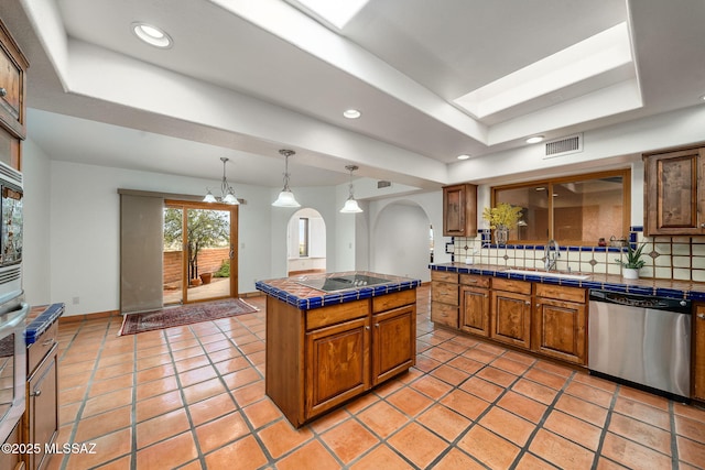 kitchen featuring tile counters, a center island, sink, stainless steel dishwasher, and backsplash