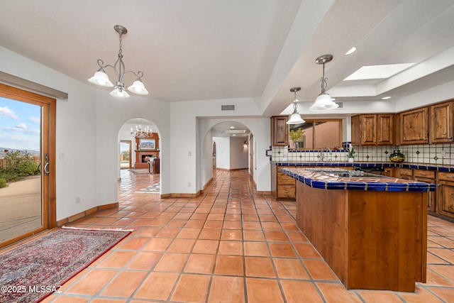 kitchen featuring pendant lighting, a notable chandelier, light tile patterned floors, and tasteful backsplash