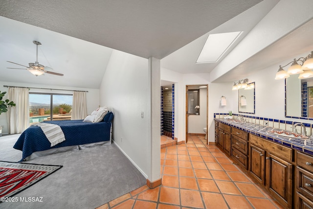 interior space featuring light carpet, vaulted ceiling with skylight, ceiling fan, and sink