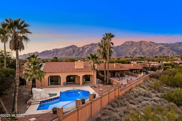 pool at dusk featuring a patio area and a mountain view