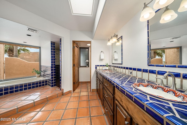 bathroom featuring tile patterned floors, vanity, a washtub, and a skylight