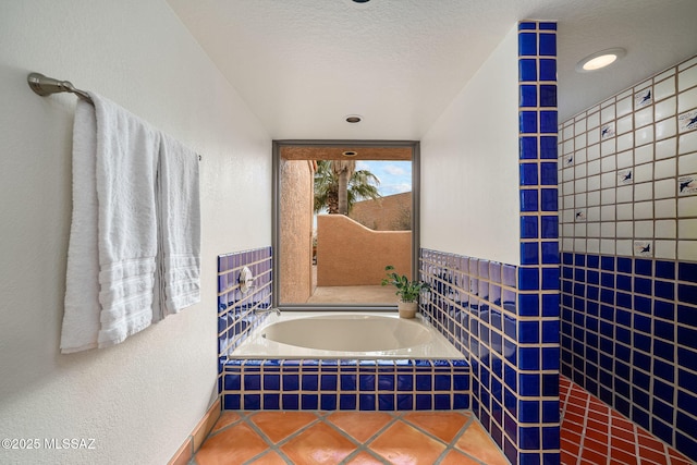 bathroom featuring tile patterned flooring, a textured ceiling, and tiled bath