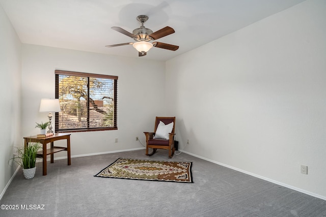 sitting room with ceiling fan and dark colored carpet