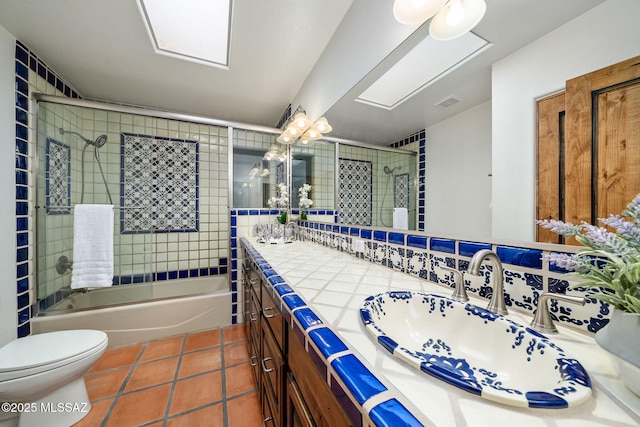 full bathroom featuring vanity, shower / bath combination with glass door, tile patterned flooring, decorative backsplash, and toilet