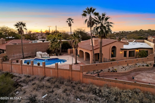 pool at dusk with a patio area