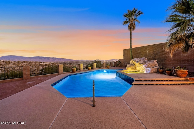 pool at dusk with a mountain view and a patio