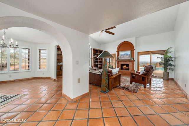 living room featuring tile patterned flooring, ceiling fan with notable chandelier, and vaulted ceiling