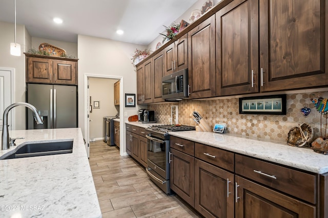 kitchen featuring pendant lighting, backsplash, sink, light stone counters, and stainless steel appliances