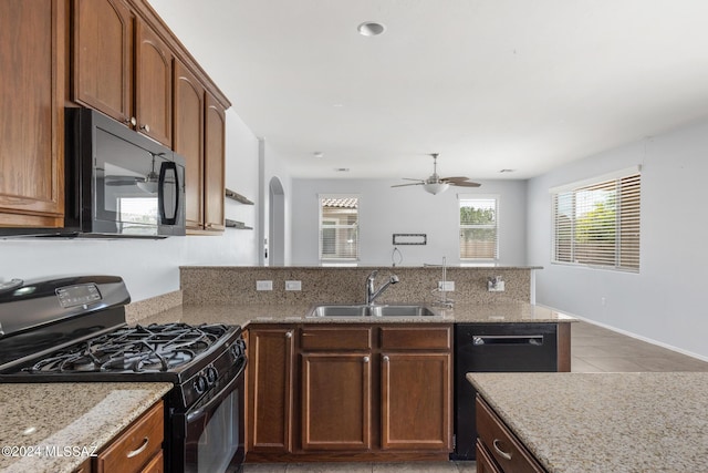 kitchen with black appliances, ceiling fan, sink, and light stone counters