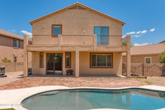 back of house featuring a fenced in pool, a balcony, and a patio