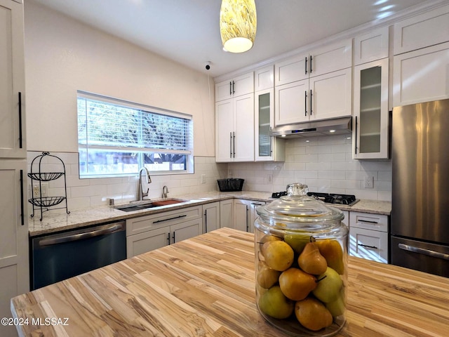 kitchen featuring appliances with stainless steel finishes, light stone counters, white cabinetry, and sink