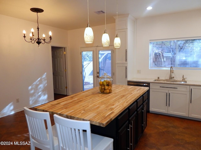 kitchen featuring pendant lighting, white cabinetry, a kitchen island, and sink