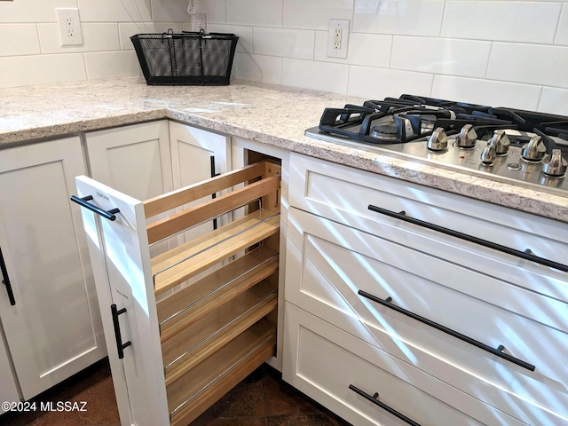 interior space with light stone countertops, tasteful backsplash, white cabinetry, and stainless steel gas stovetop