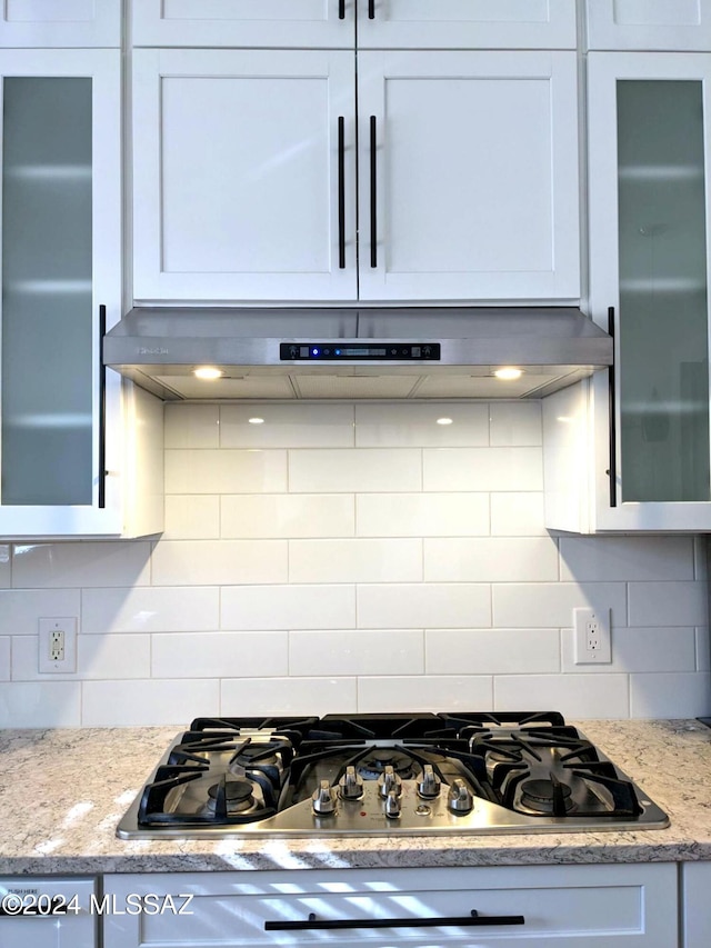 kitchen featuring backsplash, light stone countertops, white cabinets, and stainless steel gas stovetop