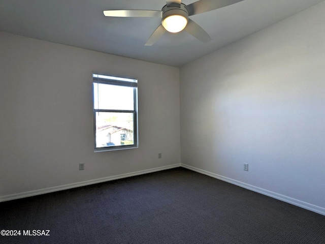 spare room featuring ceiling fan and dark carpet