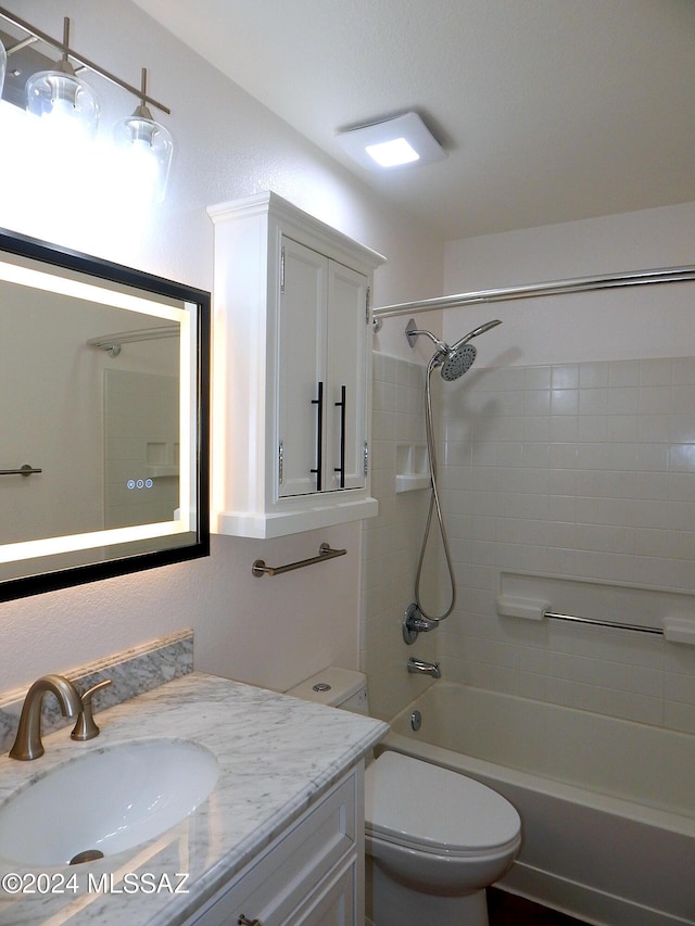 full bathroom featuring vanity, tiled shower / bath combo, and toilet