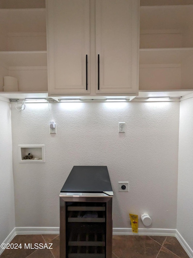 washroom with electric dryer hookup, cabinets, washer hookup, and dark tile patterned flooring