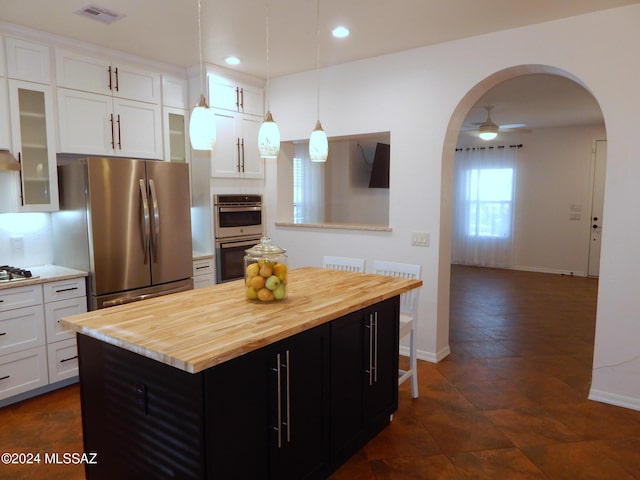 kitchen with stainless steel appliances, ceiling fan, decorative light fixtures, white cabinets, and a kitchen island