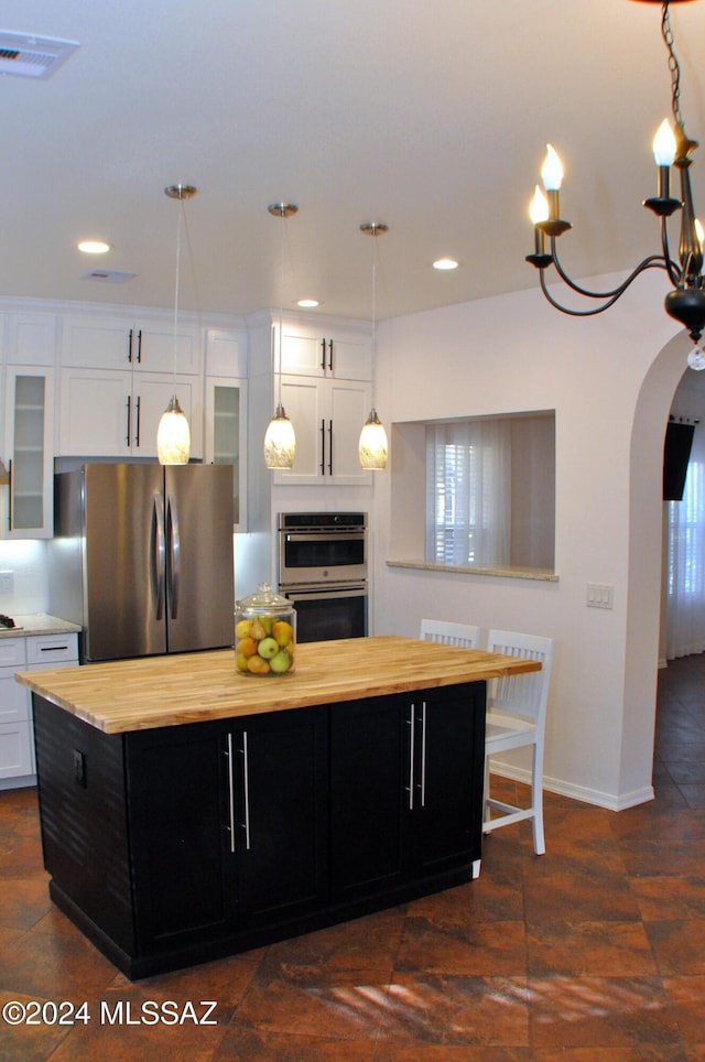 kitchen featuring white cabinets, a center island, appliances with stainless steel finishes, and a chandelier