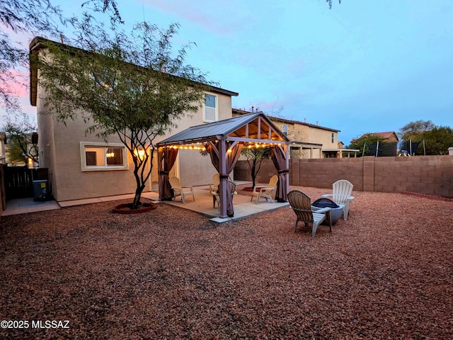 back house at dusk with a gazebo and a patio area