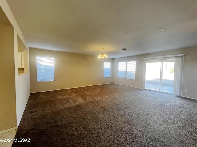 empty room featuring dark carpet and a chandelier