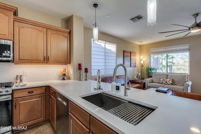 kitchen with ceiling fan, sink, kitchen peninsula, pendant lighting, and appliances with stainless steel finishes