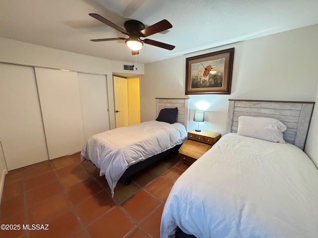 bedroom with dark tile patterned floors, a closet, and ceiling fan