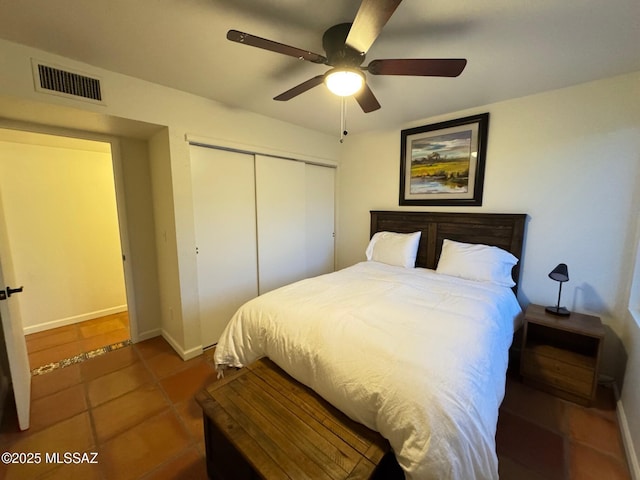 bedroom with a closet, dark tile patterned flooring, and ceiling fan