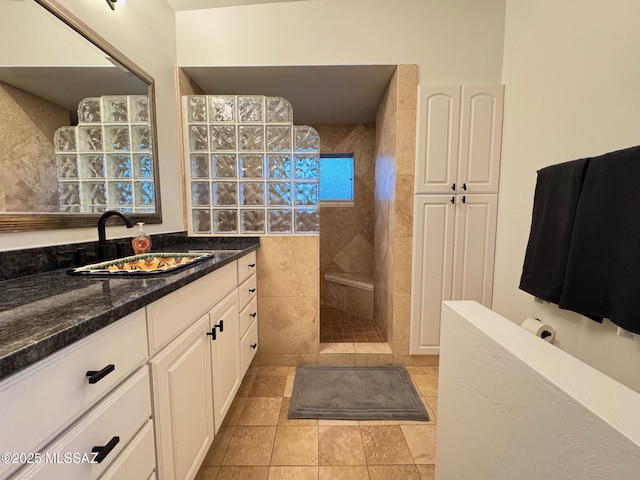 bathroom featuring tile patterned flooring, vanity, and tiled shower