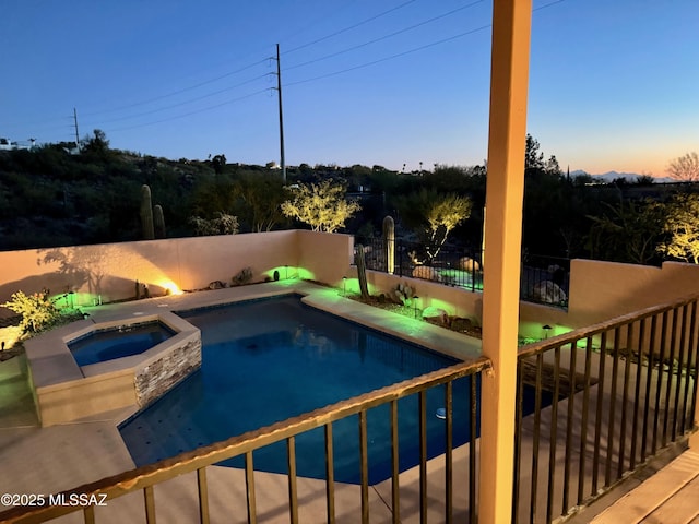 pool at dusk with an in ground hot tub