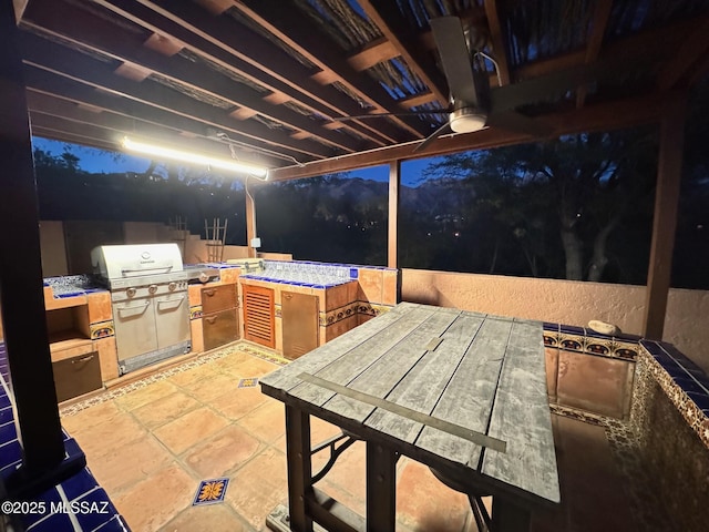 view of patio with area for grilling, ceiling fan, and a grill