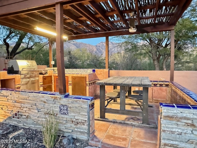 view of patio with a pergola, area for grilling, and a mountain view