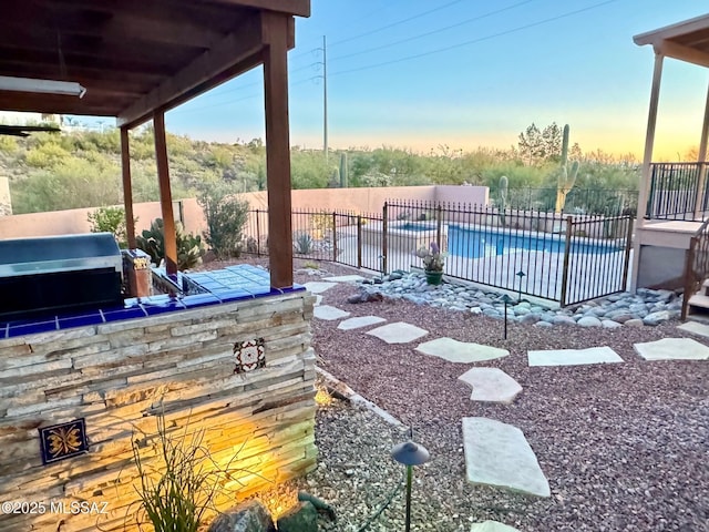 patio terrace at dusk featuring a fenced in pool