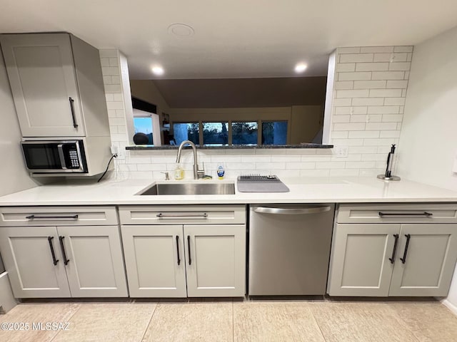 kitchen with tasteful backsplash, gray cabinetry, stainless steel appliances, sink, and light tile patterned floors