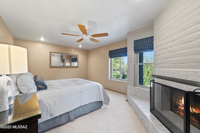 bedroom with a tile fireplace, ceiling fan, and carpet