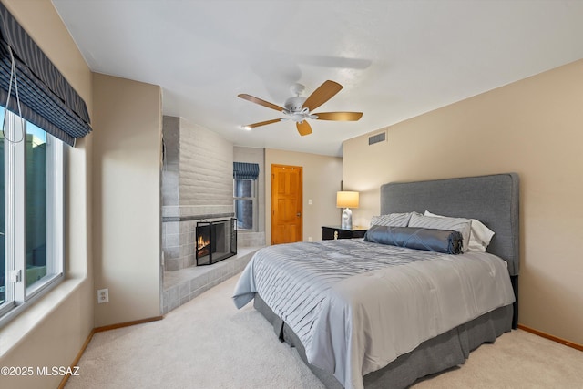 carpeted bedroom with ceiling fan and a brick fireplace