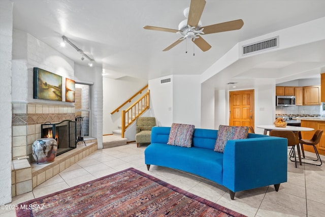 living room with light tile patterned floors, stairway, visible vents, and a tile fireplace