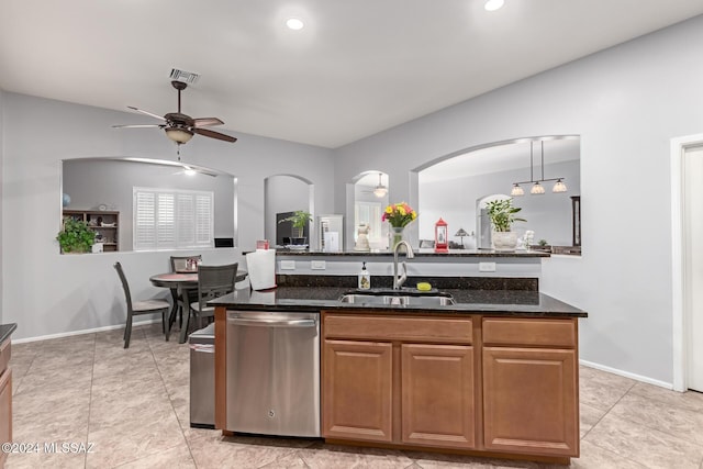 kitchen featuring stainless steel dishwasher, ceiling fan, sink, pendant lighting, and dark stone countertops