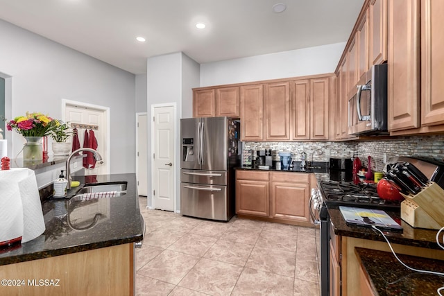 kitchen with sink, dark stone countertops, decorative backsplash, light tile patterned flooring, and appliances with stainless steel finishes