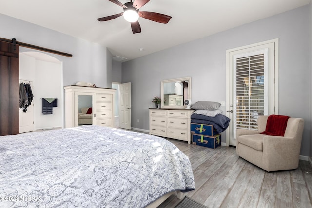 bedroom featuring wood-type flooring, a barn door, and ceiling fan