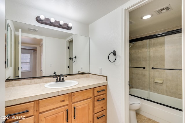 full bathroom featuring a textured ceiling, vanity, enclosed tub / shower combo, tile patterned flooring, and toilet