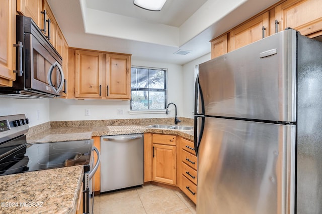 kitchen featuring a raised ceiling, sink, light stone countertops, light tile patterned floors, and appliances with stainless steel finishes